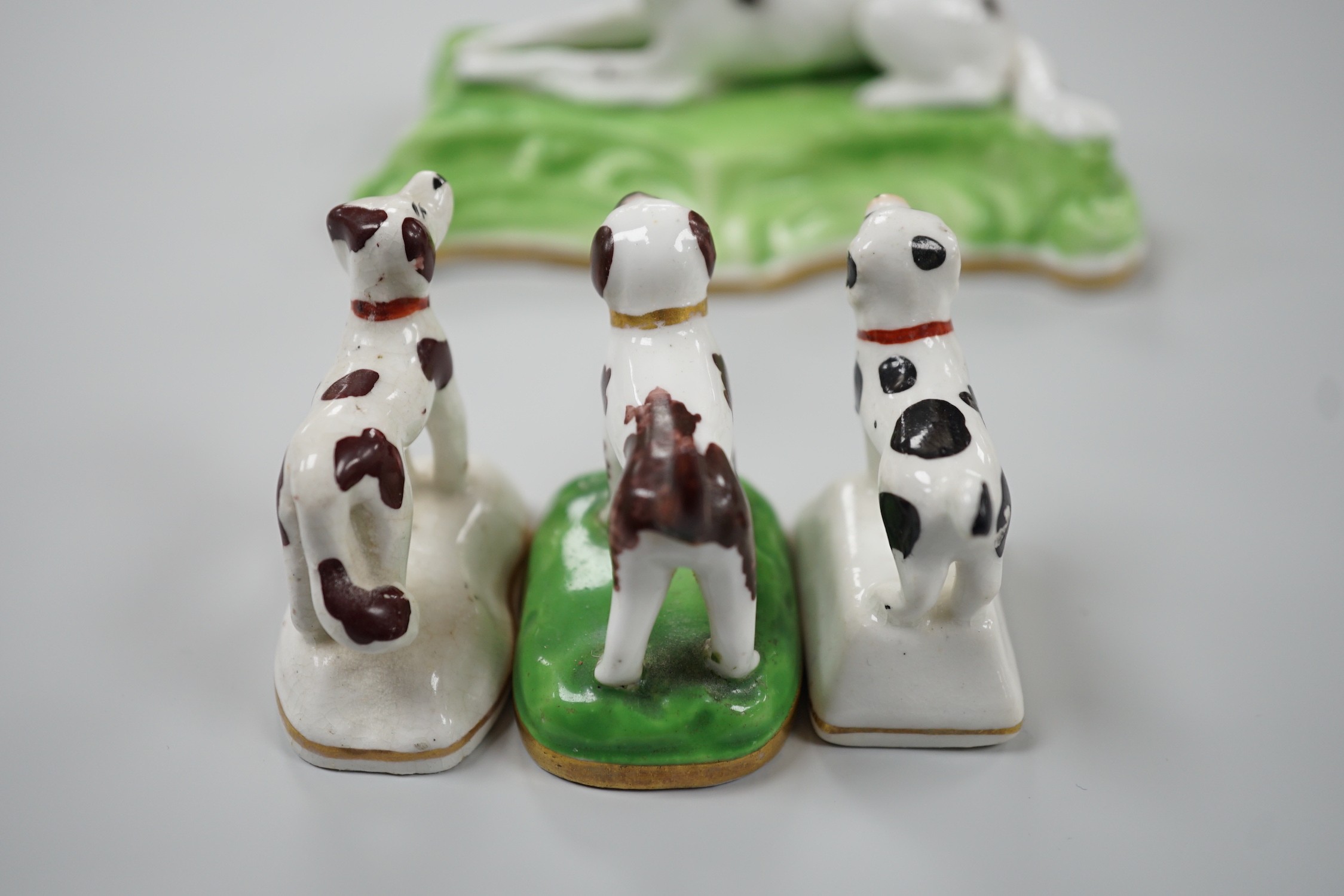 Three toy Staffordshire models of standing terriers; two with brown spots and the other black spots, together with a small Staffordshire model of a recumbent black and white setter on modelled base. c.1830-50, Largest 13